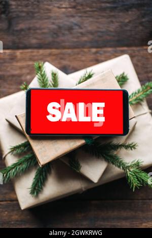 Soldes de Noël, achats en ligne de Noël, ventes de vacances d'hiver, Vendredi fou. Téléphone cellulaire avec écran rouge texte de vente sur la pile de boîtes-cadeaux de noël avec Banque D'Images