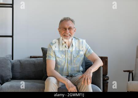 Beau et heureux homme âgé d'âge mûr reposant sur un canapé confortable. Banque D'Images