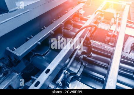 Arrière-plan industriel. Courroie de convoyeur de machine de formage de tôles en usine. Fabrication de tuiles de toit. Banque D'Images