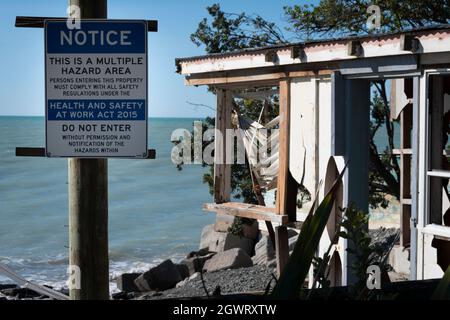 Panneau de danger en face de la maison détruit par l'érosion côtière et l'élévation du niveau de la mer, Haumoana Beach, Hawkes Bay, Île du Nord, Nouvelle-Zélande Banque D'Images