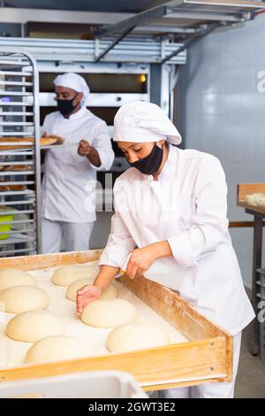 Boulanger féminin arroser de l'eau les pains façonnés avant des cuire Banque D'Images