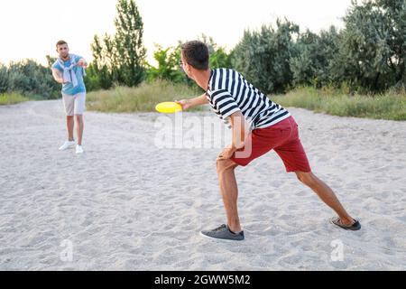 Jeunes hommes jouant au Frisbee sur la plage Banque D'Images