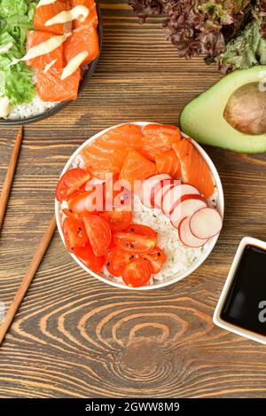 Délicieux poke bols avec saumon, légumes et sauce sur fond de bois Banque D'Images