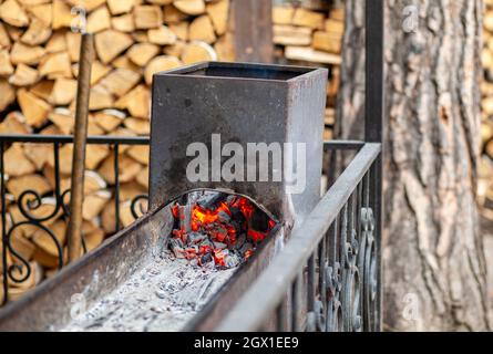 Brûlage de charbons dans un gril en métal pour faire frire de la viande et des légumes. Cuisiner sur un feu de camp. Banque D'Images
