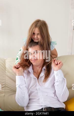 Père et sa fille s'amusent dans leur salon. Petite fille ont la main blessée mais elle est heureuse être ensemble son père. Banque D'Images