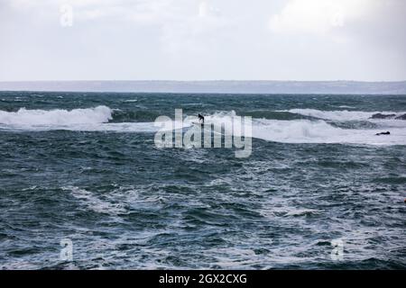 Les surfeurs apprécient la mer agitée lors d'une journée automnale ensoleillée et Breezy à Porthleven, Cornouailles. Banque D'Images