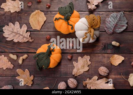Artisanat automne encore la vie: Citrouilles tricotées et feuilles sur fond de bois. Décoration Halloween et Thanksgiving Banque D'Images
