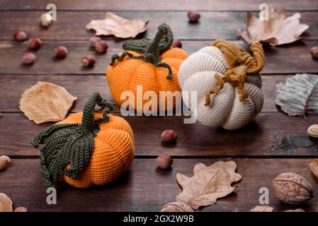 Artisanat automne encore la vie: Citrouilles tricotées et feuilles sur fond de bois. Décoration Halloween et Thanksgiving Banque D'Images