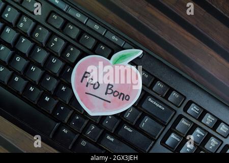 Pro bono écrire sur les notes adhésives isolées sur la table en bois. Banque D'Images