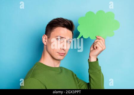 Photo de confiant intelligent gars tenir la parole bulle porter le pull-over vert isolé couleur bleu arrière-plan Banque D'Images