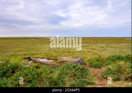 L'épave d'un bateau en bois posé pour se reposer sur le marais de la réserve naturelle de Blakeney, Norfolk, Angleterre. Banque D'Images