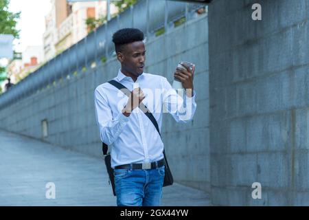 portrait du jeune homme d'affaires afro-américain qui boit un café dans la rue avec une expression triomphante Banque D'Images