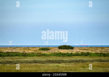 Vue de Blakeney Freshes à Race Bank Wind Farm et un navire de fret à l'horizon dans la mer du Nord, Norfolk, Angleterre. Banque D'Images