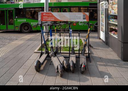 Les scooters électriques se trouvent sur le trottoir, sur fond d'un bus public, avec les règles de location via Internet, une application en russe. Banque D'Images