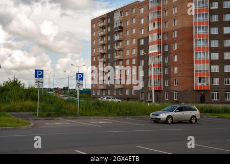 La voiture se trouve près du parking pour les personnes handicapées sur le fond d'un immeuble résidentiel en été. Banque D'Images