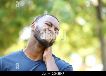 Un homme noir se plaint de maux de cou dans un parc Banque D'Images