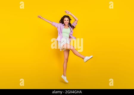 Pleine longueur de taille de corps photo femme saut haut dansant à la fête isolé couleur jaune vif fond Banque D'Images