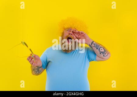 La graisse énervait l'homme avec une perruque dans la tête et des lunettes de soleil Banque D'Images
