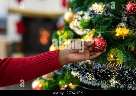 Main de la femme africaine américaine senior décorant l'arbre de noël Banque D'Images