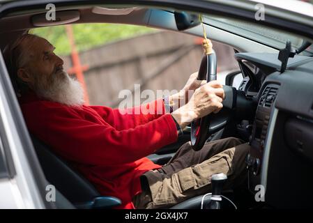 Ancien retraité senior avec voiture de conduite à longue barbe Banque D'Images
