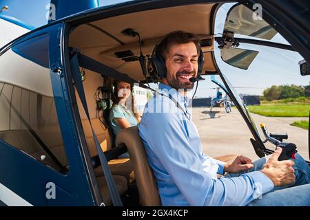 Pilote et passager posant pour caméra dans le poste de pilotage de l'hélicoptère Banque D'Images