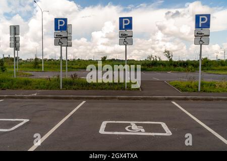 Places de stationnement pour personnes handicapées avec panneaux de signalisation routière, délimitées sur l'asphalte. Banque D'Images