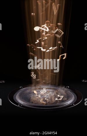 Des notes musicales dorées sortent de l'enceinte, laissant des empreintes floues. Banque D'Images