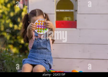 Enfant jouant avec pop il, appuyant sur les bulles avec ses doigts, vue de dessus.Nouveau jouet antistress pour les enfants et les adultes.espace de copie pour le texte ou le design Banque D'Images