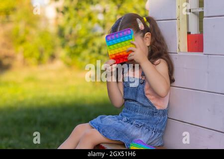 Enfant jouant avec pop il, appuyant sur les bulles avec ses doigts, vue de dessus.Nouveau jouet antistress pour les enfants et les adultes.espace de copie pour le texte ou le design Banque D'Images