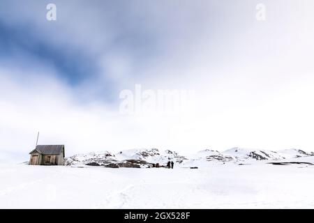 Cabine abandonnée et mine de marbre à Camp Mansfield, New London, Svalbard. Scène de montagne enneigée avec photogrpahers capturant le paysage. Banque D'Images