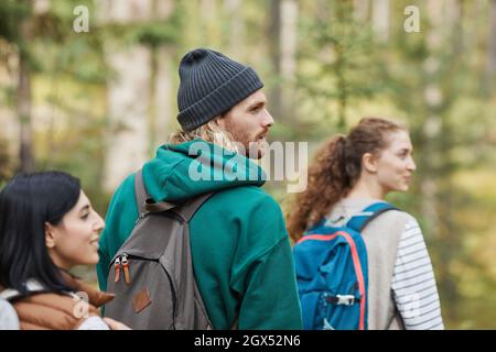 Portrait avec vue latérale d'un jeune homme barbu qui fait de la randonnée dans les bois avec des amies tout en explorant les sentiers de randonnée, l'espace de copie Banque D'Images