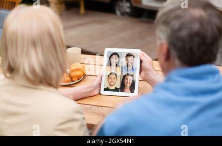 Les parents européens adultes ont un appel vidéo avec une photo d'enfants du millénaire sur un écran de tablette Banque D'Images