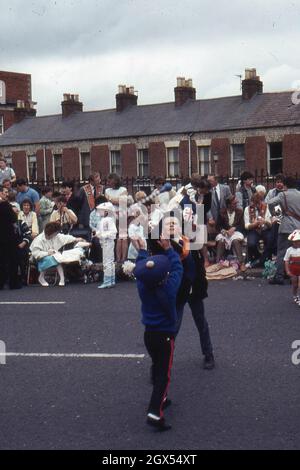 Deux garçons tourneront un bâton dans le cadre des célébrations loyalistes du 12 juillet, près de Sandy Row, Belfast 1983 Banque D'Images