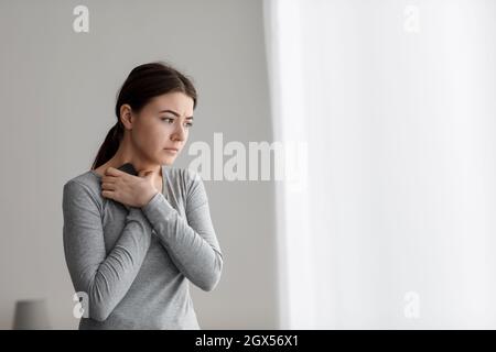 Une jeune femme cachue mécontent et désappariée embrasse son téléphone à la poitrine après de mauvaises nouvelles ou une rupture Banque D'Images