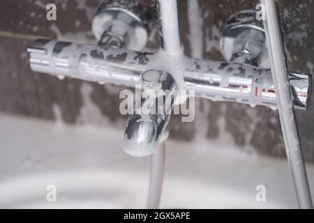 Robinet en acier avec mousse de savon dans la salle de bains Banque D'Images