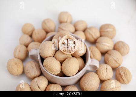 Beaucoup de noix entières dans une tasse sur fond blanc gros plan. Alimentation saine et biologique à haute teneur en protéines. Banque D'Images