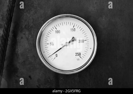 Thermomètre axial monté dans un poêle en acier rouillé, gros plan vintage stylisé photo noir et blanc Banque D'Images
