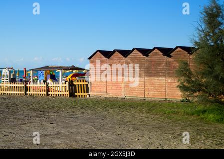 Vue sur la plage vide - chaises longues rouges et parasols jaunes près de l'eau de mer, sable doré, montagnes à l'horizon et ciel clair Banque D'Images