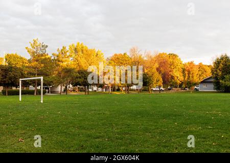 Parc public et terrain de football avec herbe verte et portes en automne dans la soirée pendant le coucher du soleil. Banque D'Images