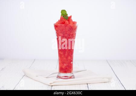 Jus de menthe de pastèque, morceau de pastèque arrangé dans un verre blanc transparent avec des feuilles de menthe arrangé un fond blanc, isolé. Banque D'Images