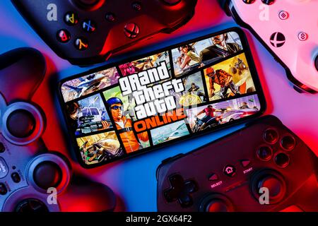 Un smartphone avec le cadre de GTA Online sur l'écran entouré de manettes de jeu. Banque D'Images