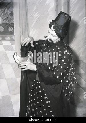 1957, historique, un homme acteur sur une scène en costume jouant le génie dans la pièce Aladdin, basé sur un conte populaire du Moyen-Orient sur le fils d'une veuve pauvre en chine qui devient le possesseur d'une lampe magique, Angleterre, Royaume-Uni. Banque D'Images