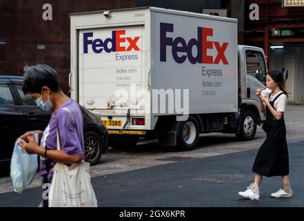 Des piétons marchent devant le camion de livraison American FedEx Express vu à Hong Kong. Banque D'Images