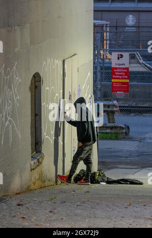 Homme mettant le graffiti sur le mur. Banque D'Images