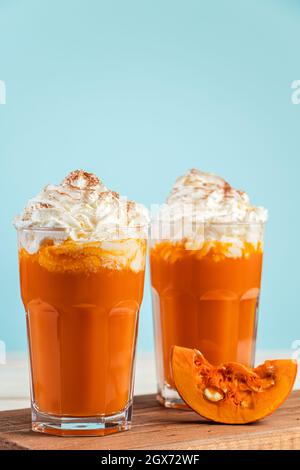 Latte citrouille épicé à la crème fouettée sur fond bleu. Deux verres de boisson chaude d'automne. Banque D'Images
