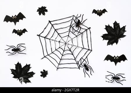 Motif Halloween avec feuilles d'érable noir, araignées et chauves-souris. Sinistre plat sur fond blanc pour la fête d'Halloween, décoration créepy pour Hallow Banque D'Images