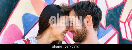 Un jeune couple amoureux rit ensemble au mur de Berlin, en Allemagne, en Europe. Portrait de heureux multiraciaux, femme asiatique, homme caucasien Banque D'Images