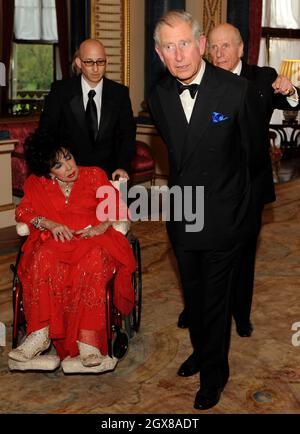 Prince Charles, Prince de Galles, Lord Rowe-Beddoe, président du Royal Welsh College (R) et actrice Dame Elizabeth Taylor, assis en fauteuil roulant, bavardent ensemble lors d'une soirée de gala au Royal Welsh College à Buckingham Palace à Londres, le 29 avril 2010. Banque D'Images