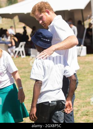Le prince Harry salue son vieil ami Mutsu Potsane, aujourd'hui âgé de 15 ans, dans les jardins du Centre pour enfants de Mamohato pour enfants atteints du VIH et du sida, lors d'une visite de retour au Lesotho en Afrique australe le 26 novembre 2015.Au cours de la visite, le prince a parlé avec amour de la perte de sa mère, Diana, la princesse de Galles et du « trou béant » qu'il avait laissé dans sa vie. Banque D'Images