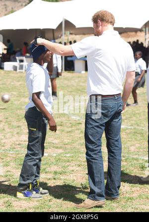 Le prince Harry salue son vieil ami Mutsu Potsane, aujourd'hui âgé de 15 ans, dans les jardins du Centre pour enfants de Mamohato pour enfants atteints du VIH et du sida, lors d'une visite de retour au Lesotho en Afrique australe le 26 novembre 2015.Au cours de la visite, le prince a parlé avec amour de la perte de sa mère, Diana, la princesse de Galles et du « trou béant » qu'il avait laissé dans sa vie. Banque D'Images